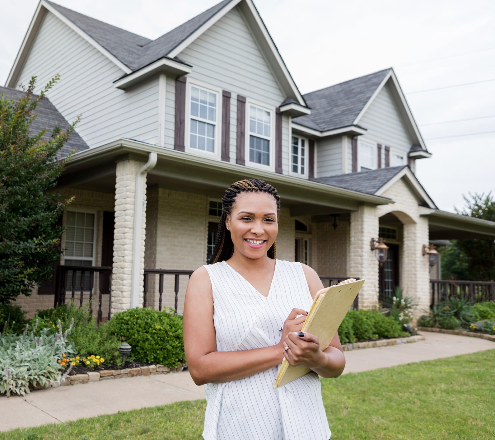 Woman holding clipboard in front of house.