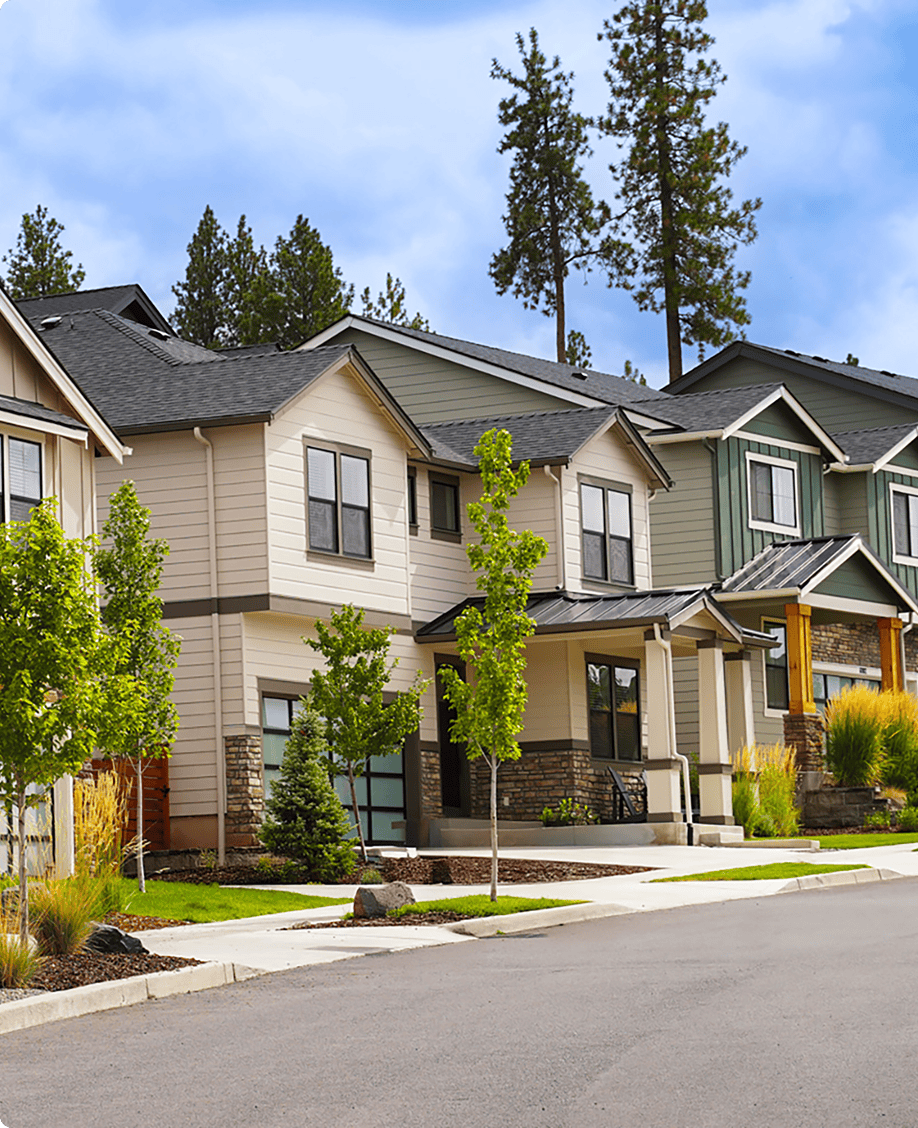 Suburban houses with trees and clear sky.