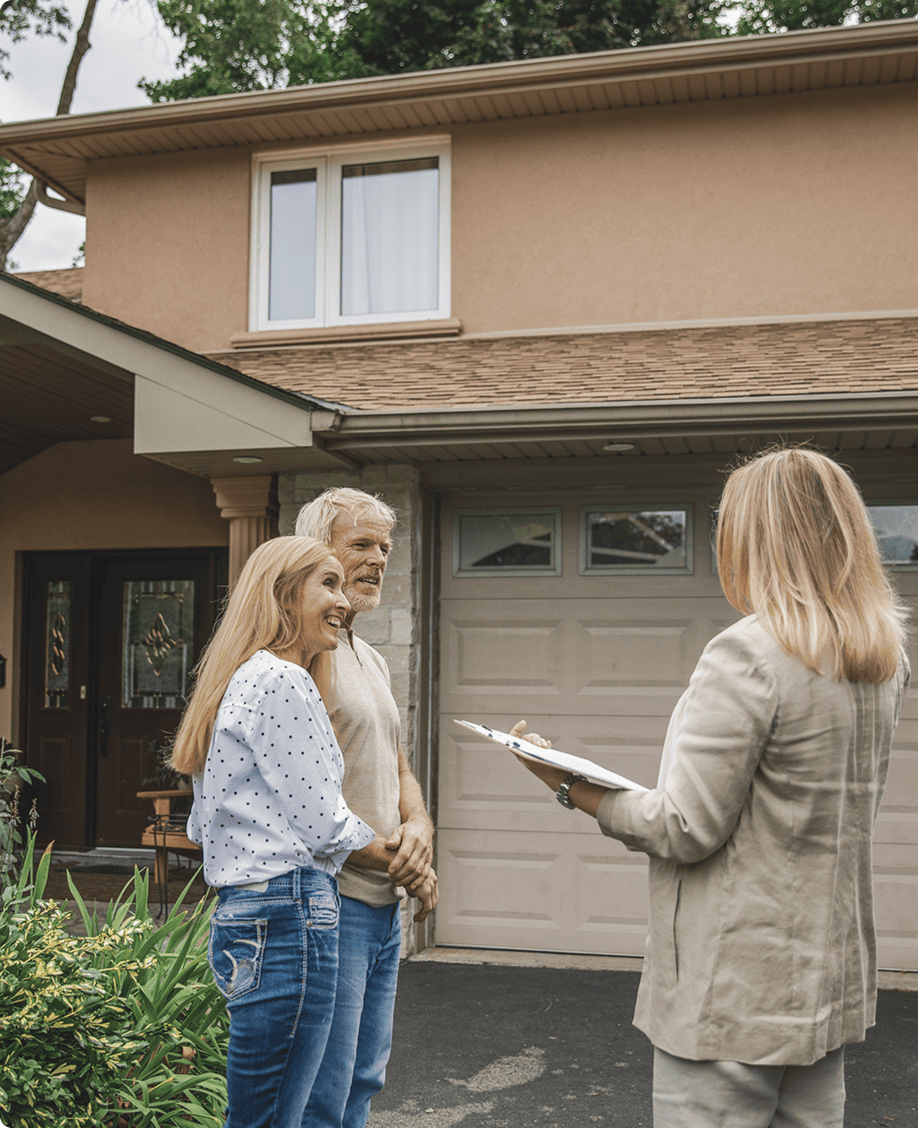 Couple meeting with realtor outside their house.